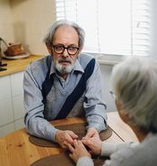 An older couple hold hands over the table