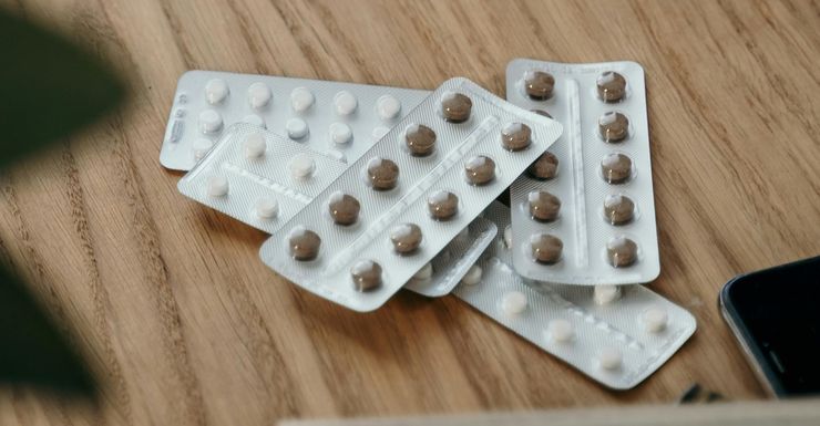 A landscape collection of medicines in blister packs on a bench.