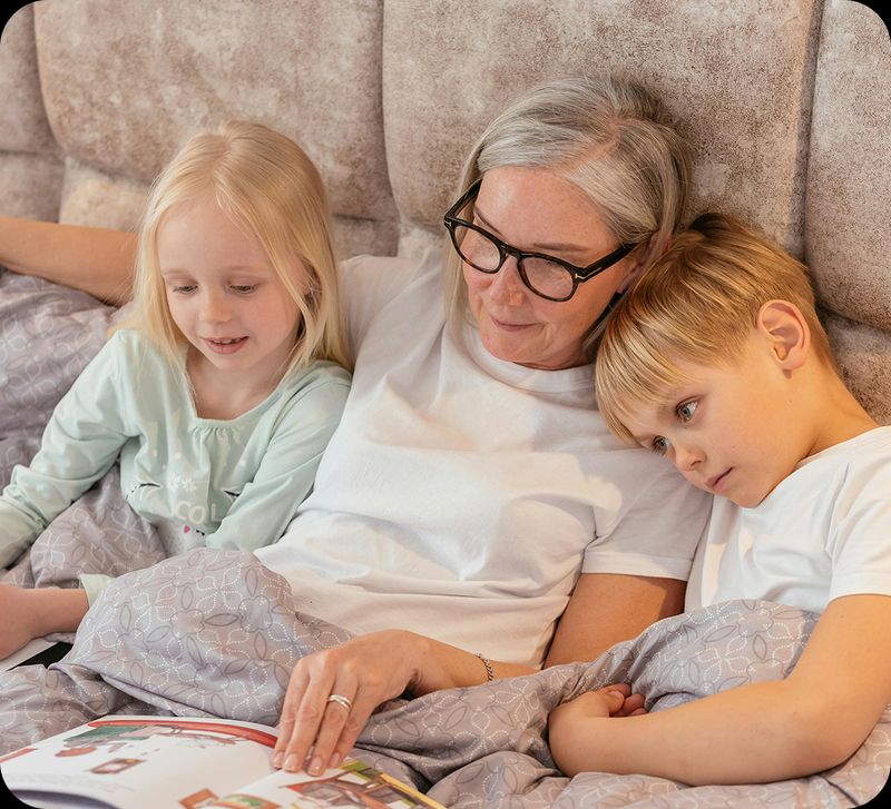 An older lady in bed, reading to her two grand children
